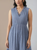 Woman wearing a blue sleeveless dress against a neutral background
