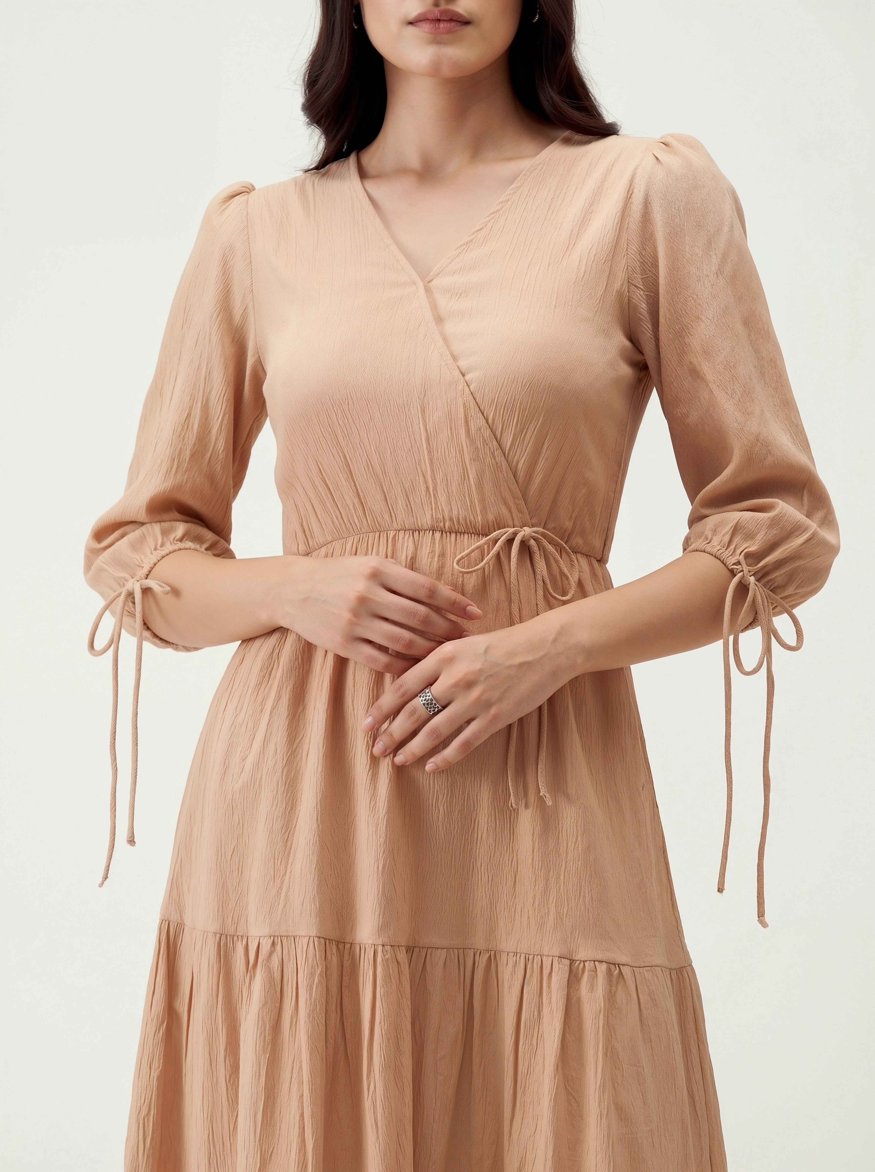 Woman wearing a beige dress with long sleeves on a white background