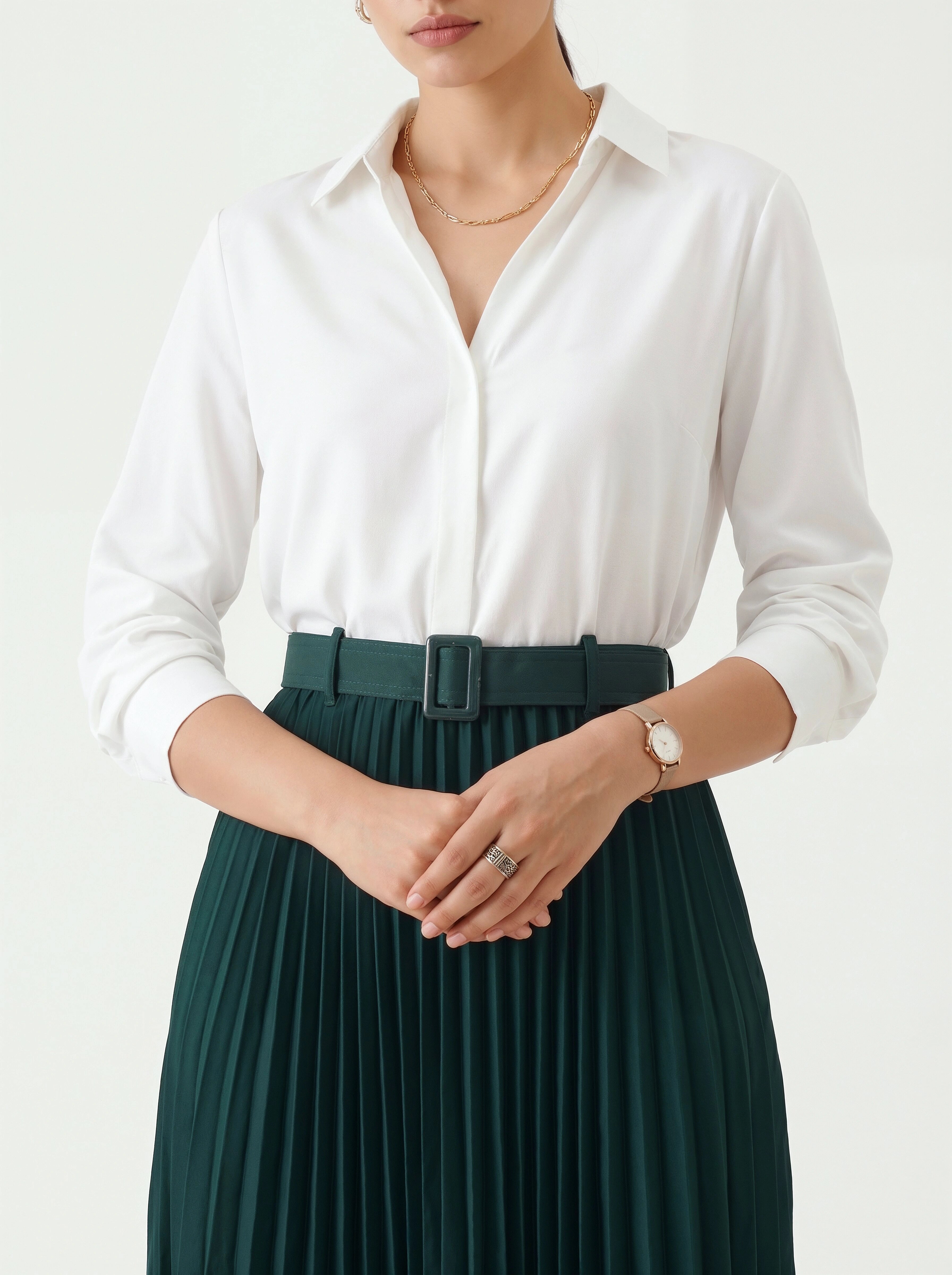 Person wearing a white shirt and green pleated skirt on a plain background