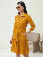 Woman wearing a mustard yellow dress with a white background