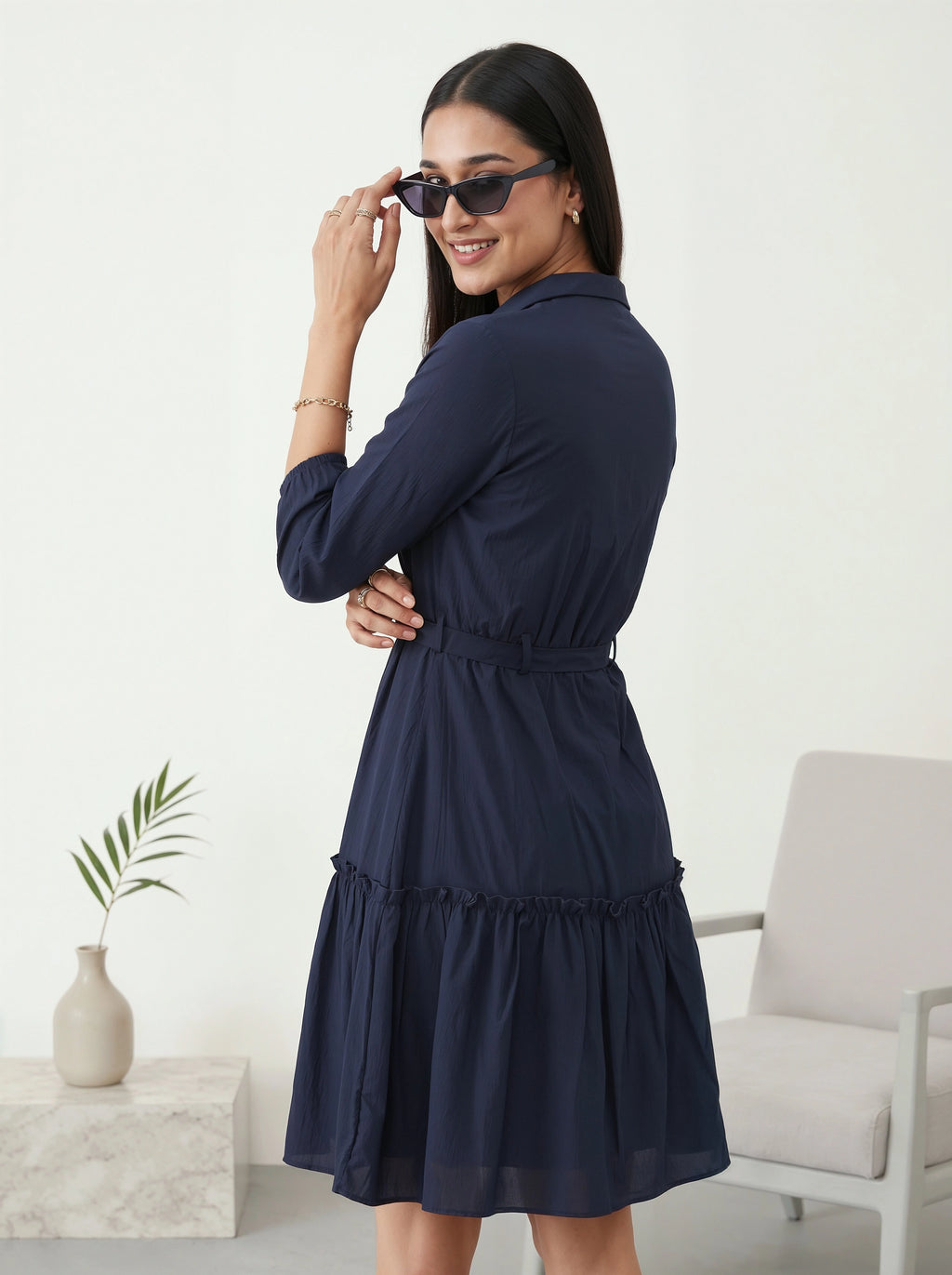 Woman wearing a navy blue dress in a minimalistic room.