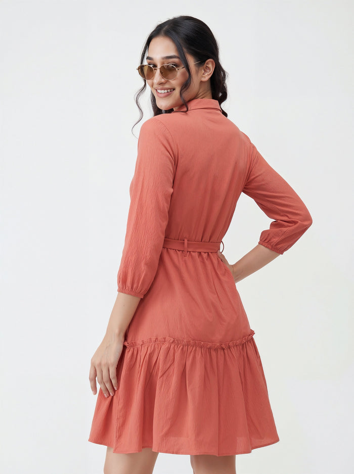 Woman wearing a coral dress with a white background
