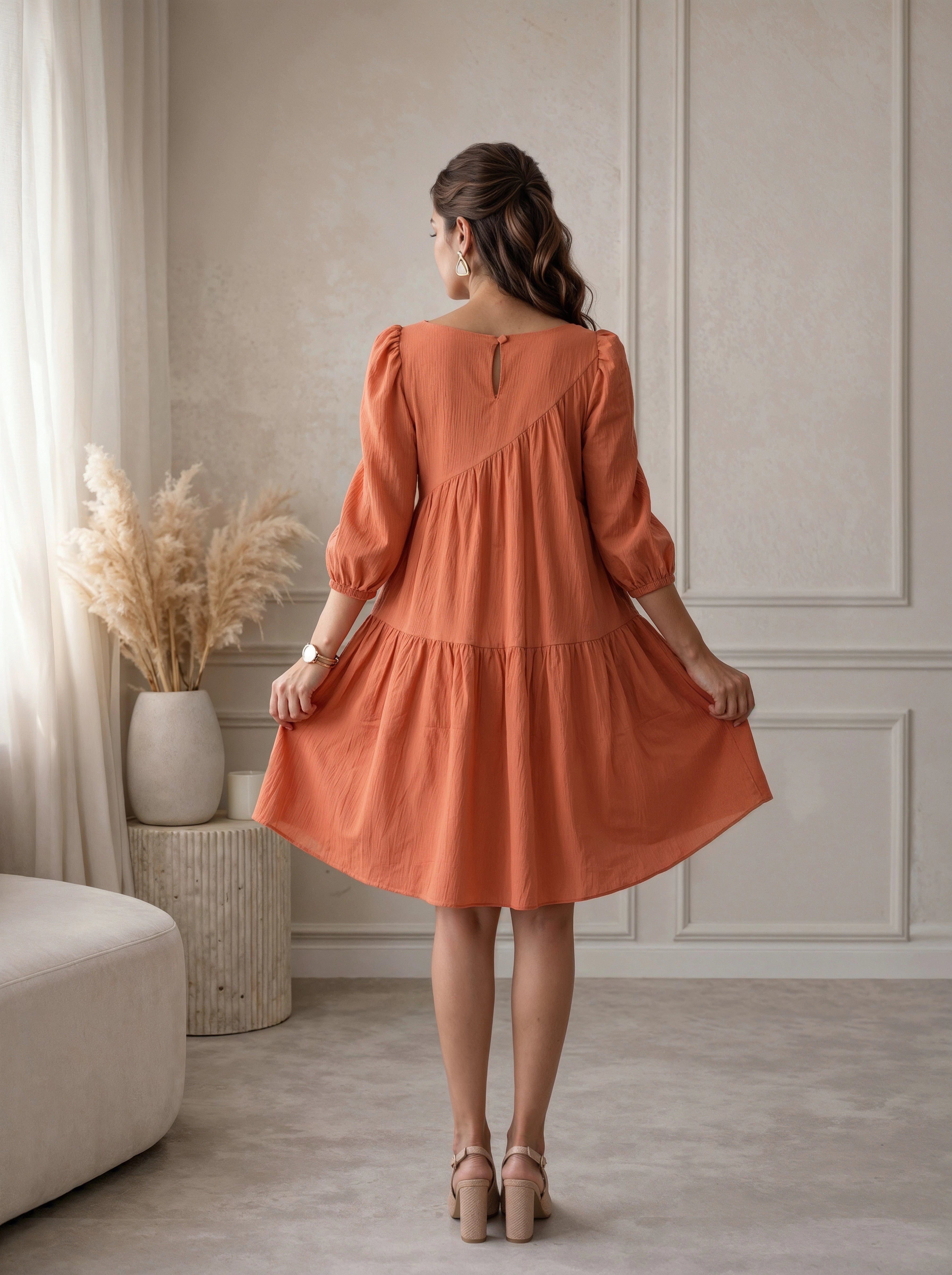 Woman wearing an orange dress in a room with neutral decor