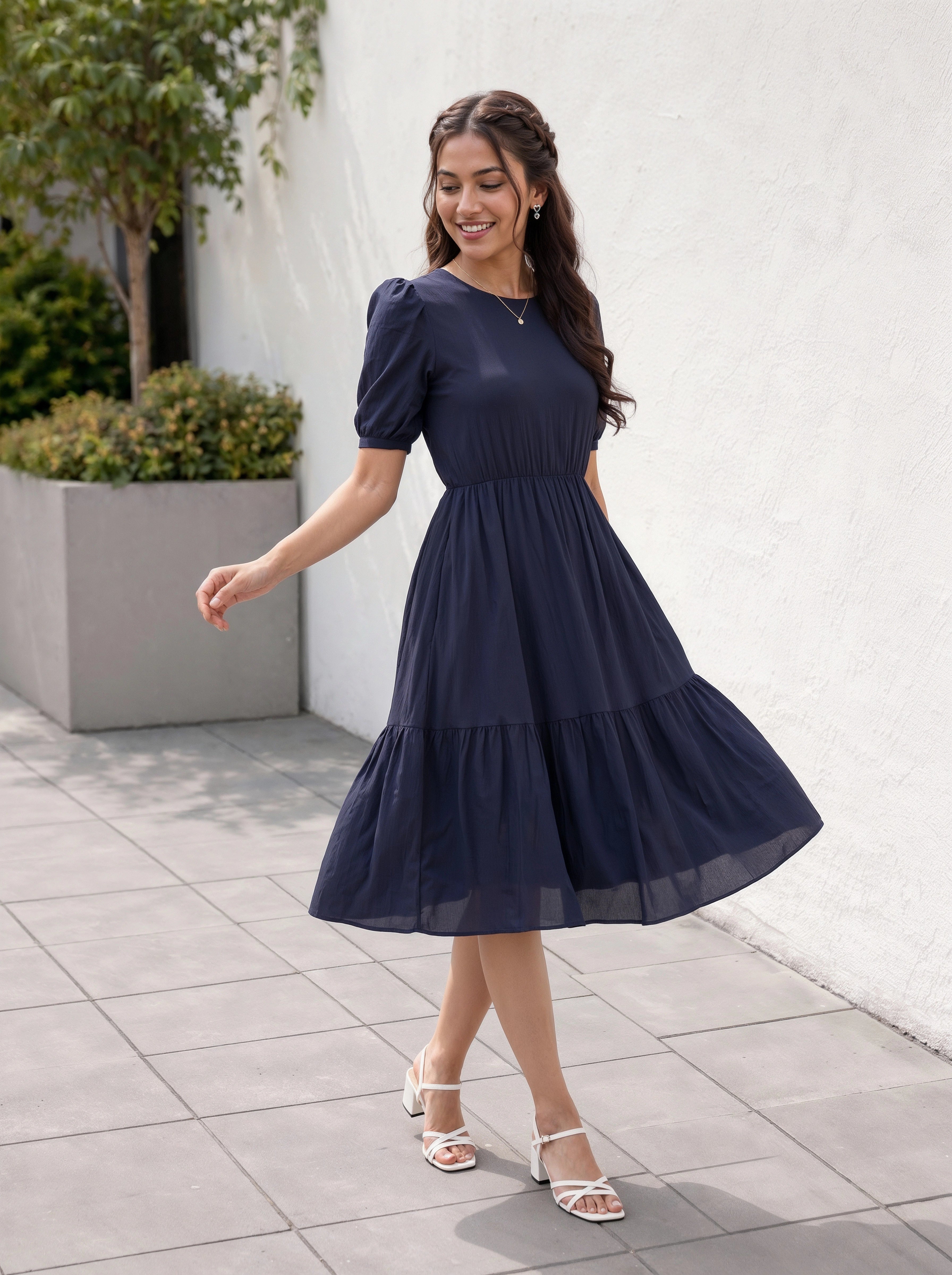 Woman in a navy blue dress standing outdoors on a tiled floor.