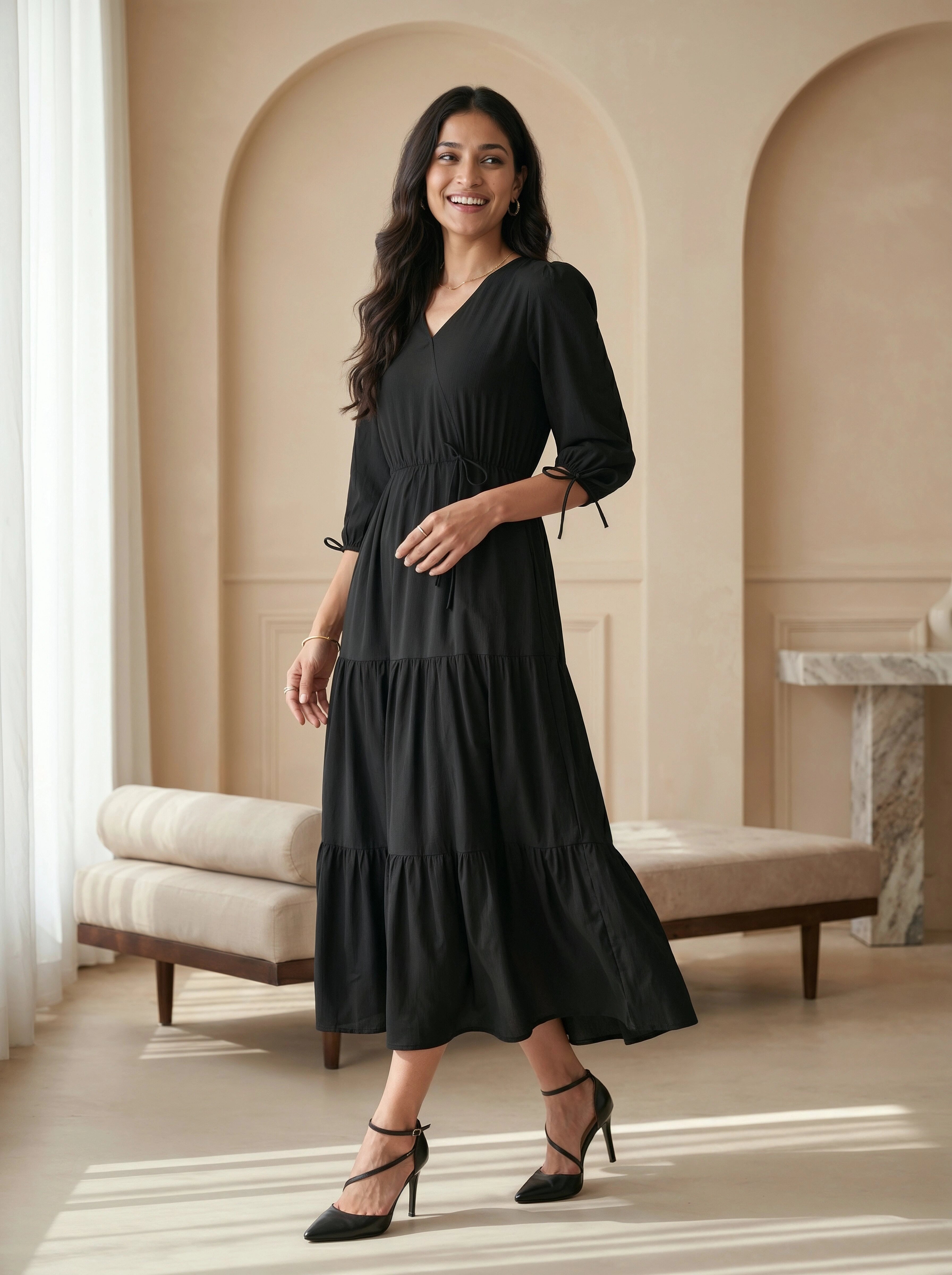 Woman wearing a black dress in an elegant room with beige walls and white curtains.
