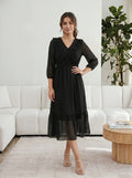 Woman in a black dress standing in a modern living room.