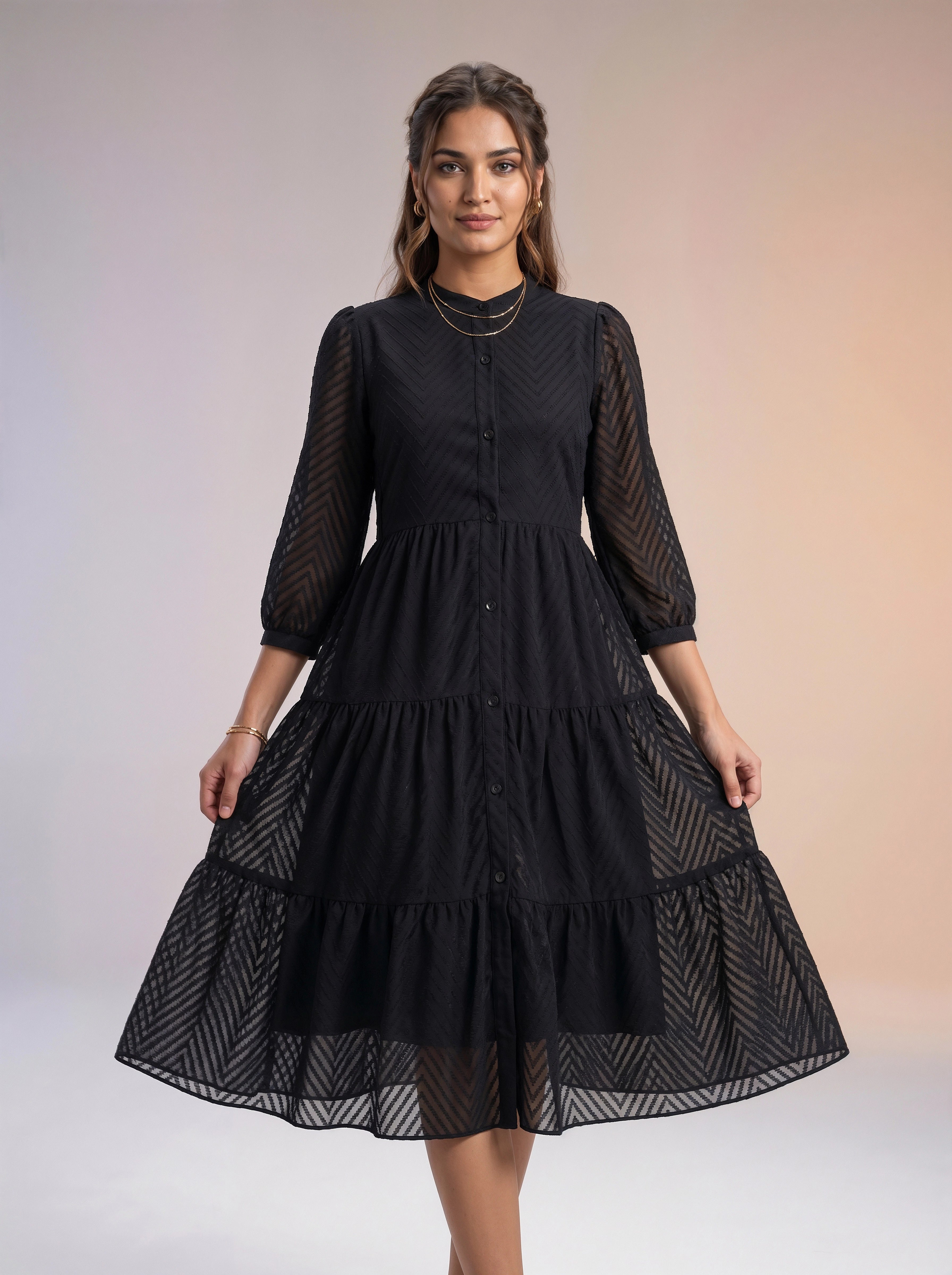 Woman wearing a black dress with sheer sleeves against a gradient background