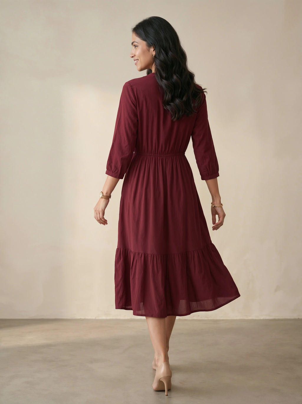 Woman wearing a burgundy dress against a plain background
