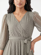 Woman wearing a gray patterned dress with a plain background