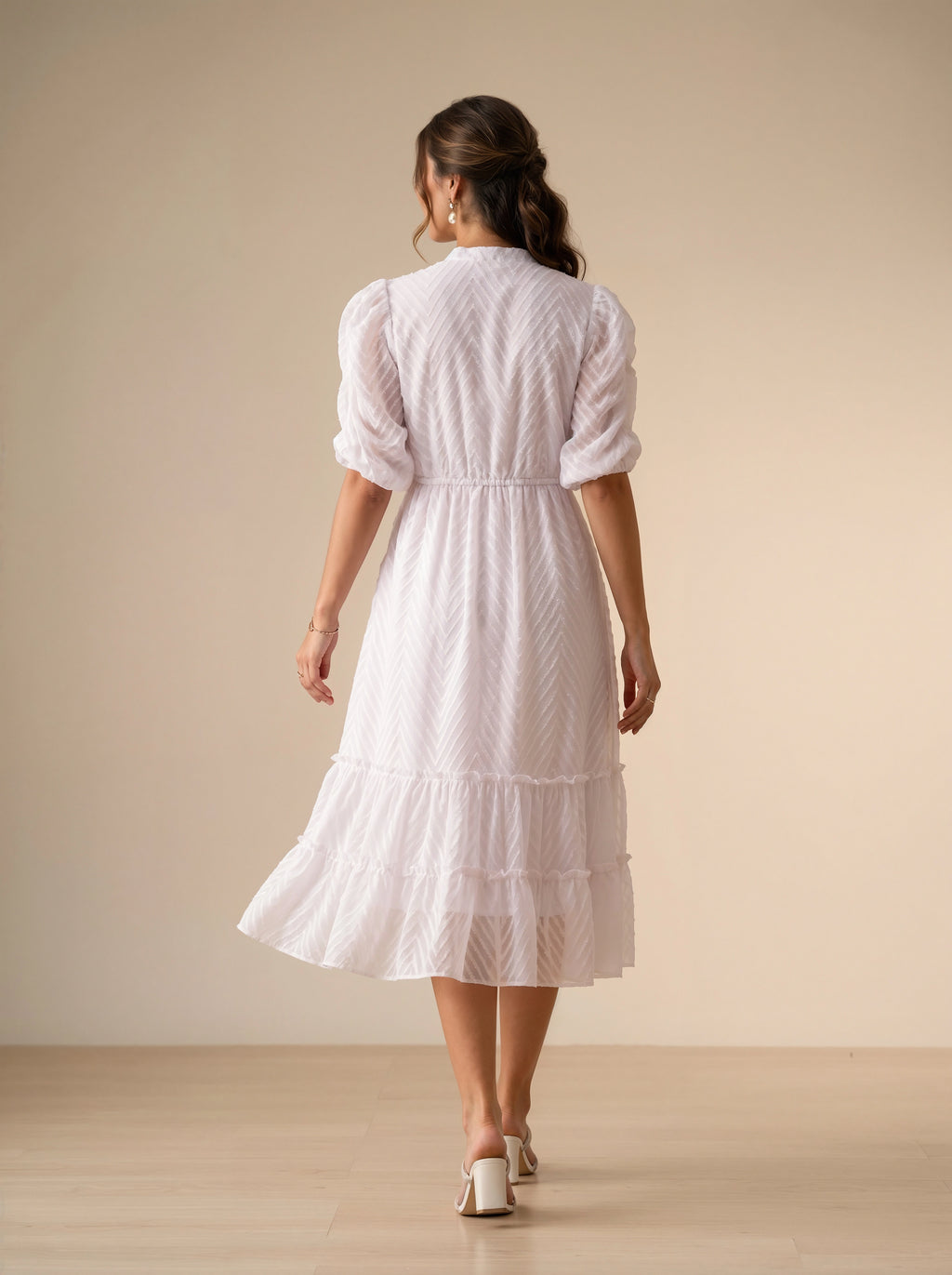 Woman wearing a white dress with ruffled details in a minimalistic setting