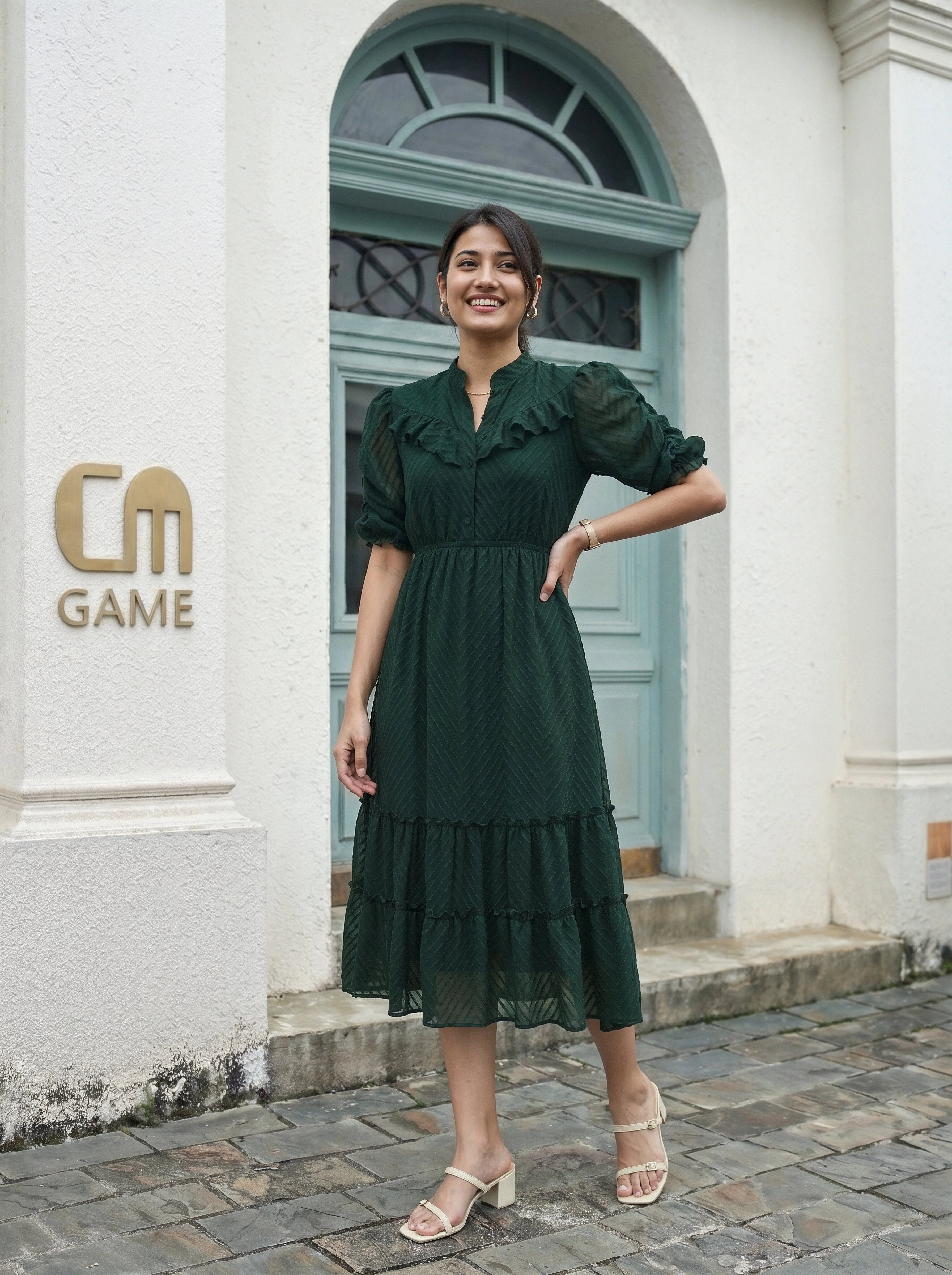 Woman in a green dress standing in front of a building with 'CM Game' logo.