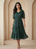 Woman wearing a green dress standing in an archway.