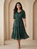 Woman wearing a green dress standing in an archway.