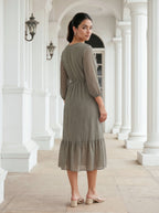 Woman in a patterned dress standing in a classical architectural setting