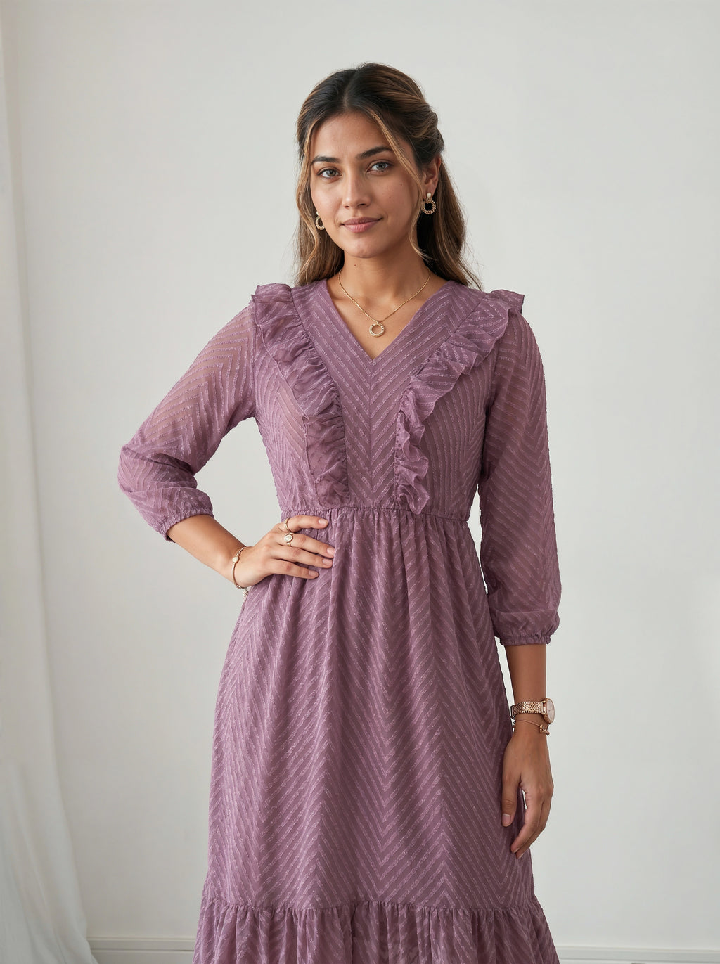 Woman wearing a purple dress with ruffled details against a plain background
