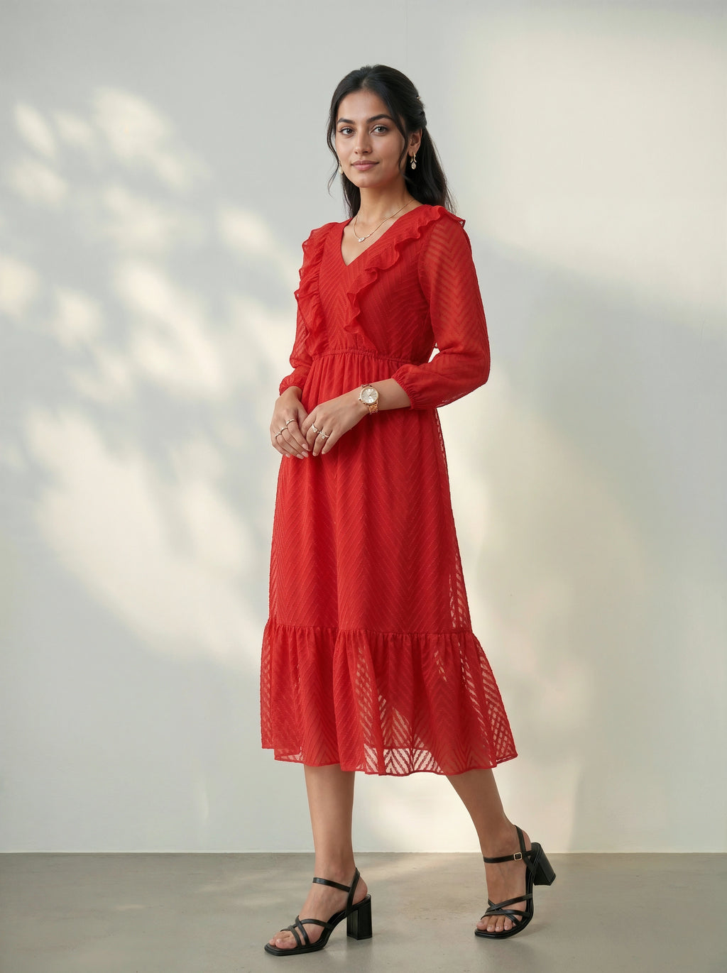 Woman wearing a red dress standing against a white wall.