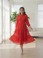 Woman in a red dress standing in a bright living room.