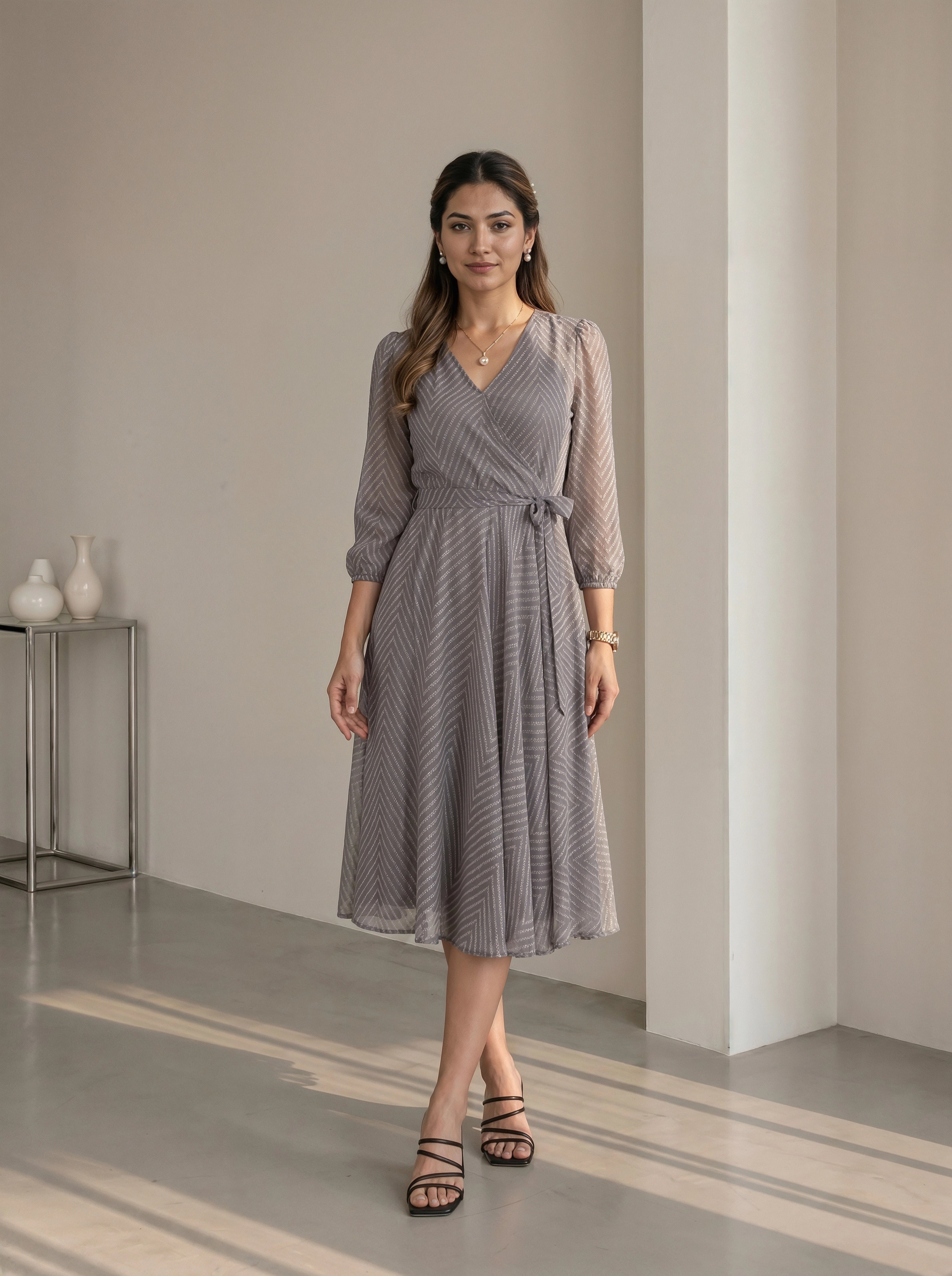 Woman wearing a gray patterned dress standing in a minimalistic room.