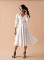 Woman wearing a white dress against a beige background