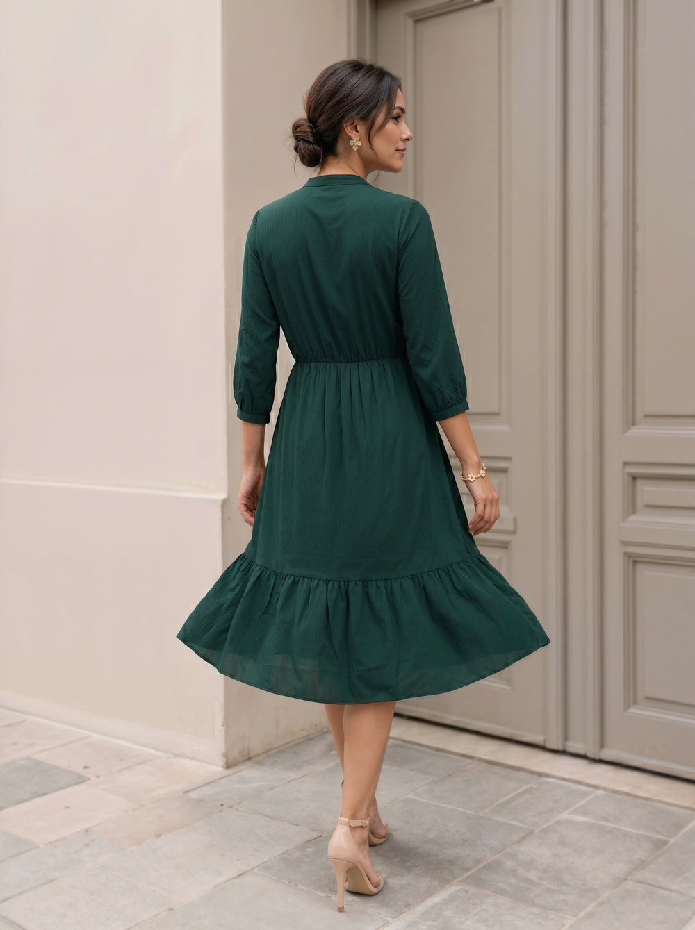 Woman wearing a green dress standing in front of a door.