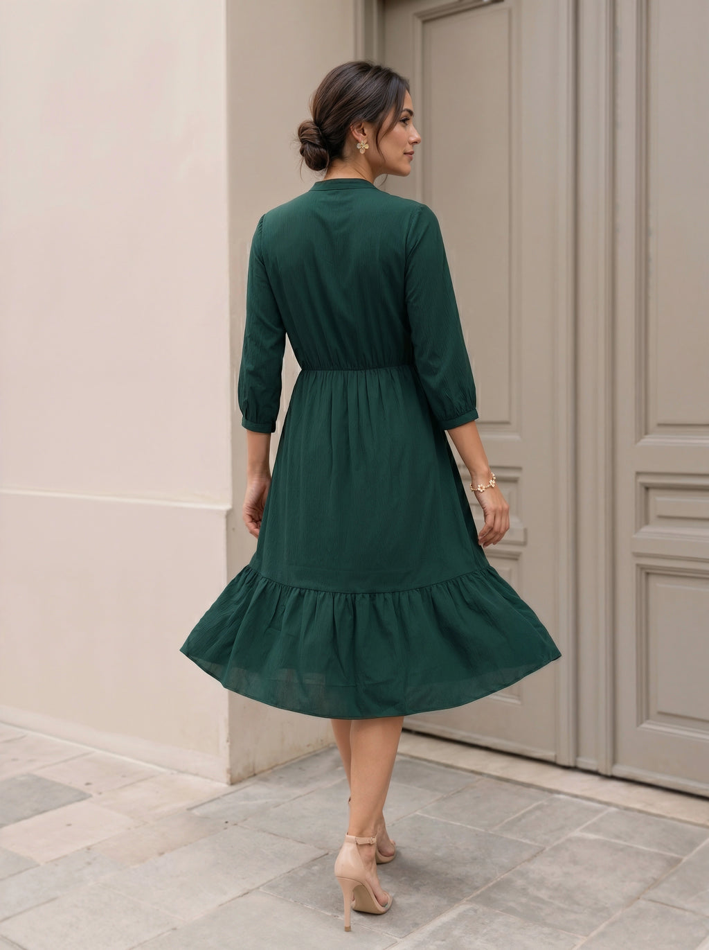 Woman wearing a green dress standing in front of a door.
