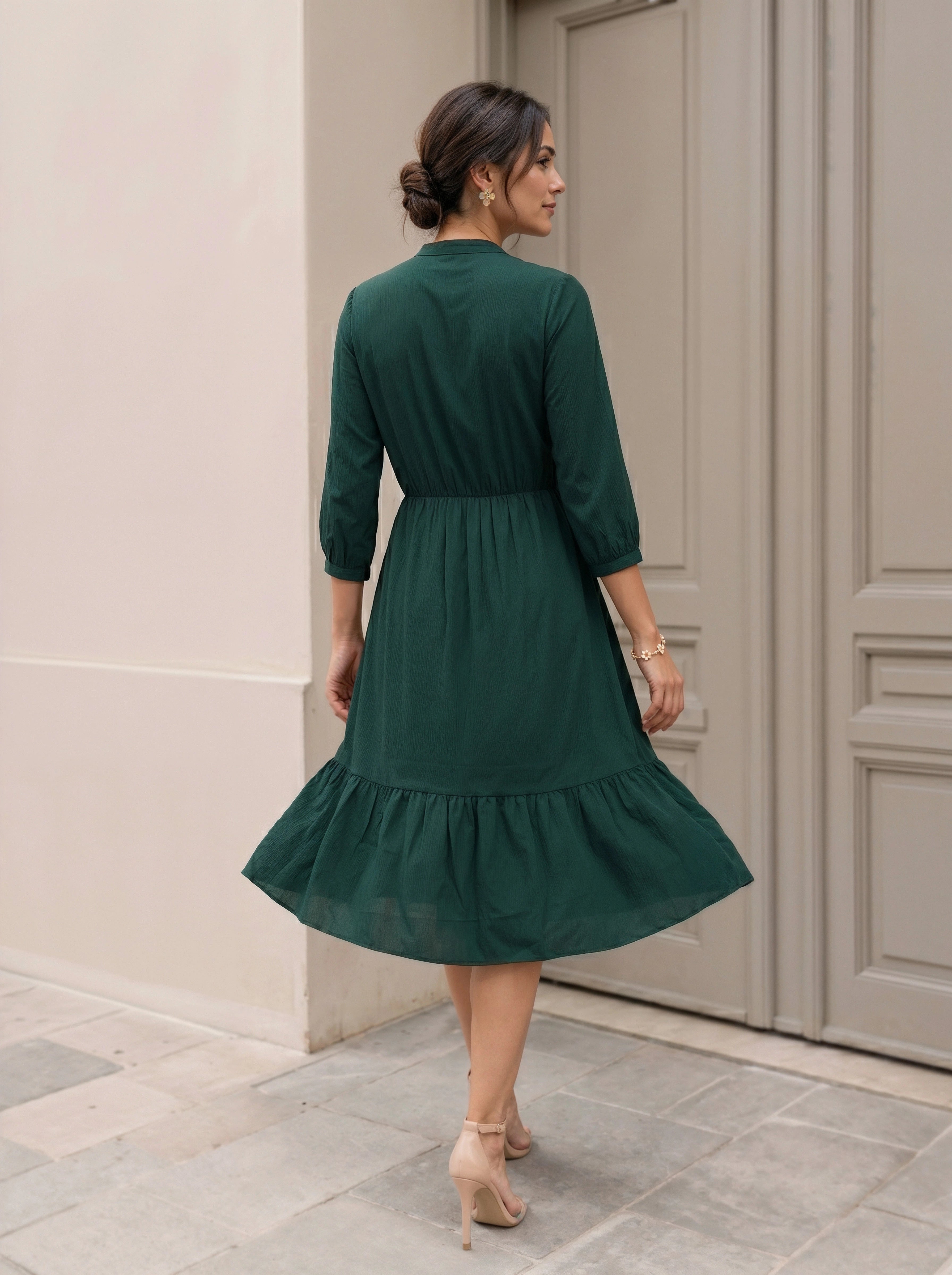 Woman wearing a green dress standing in front of a door.