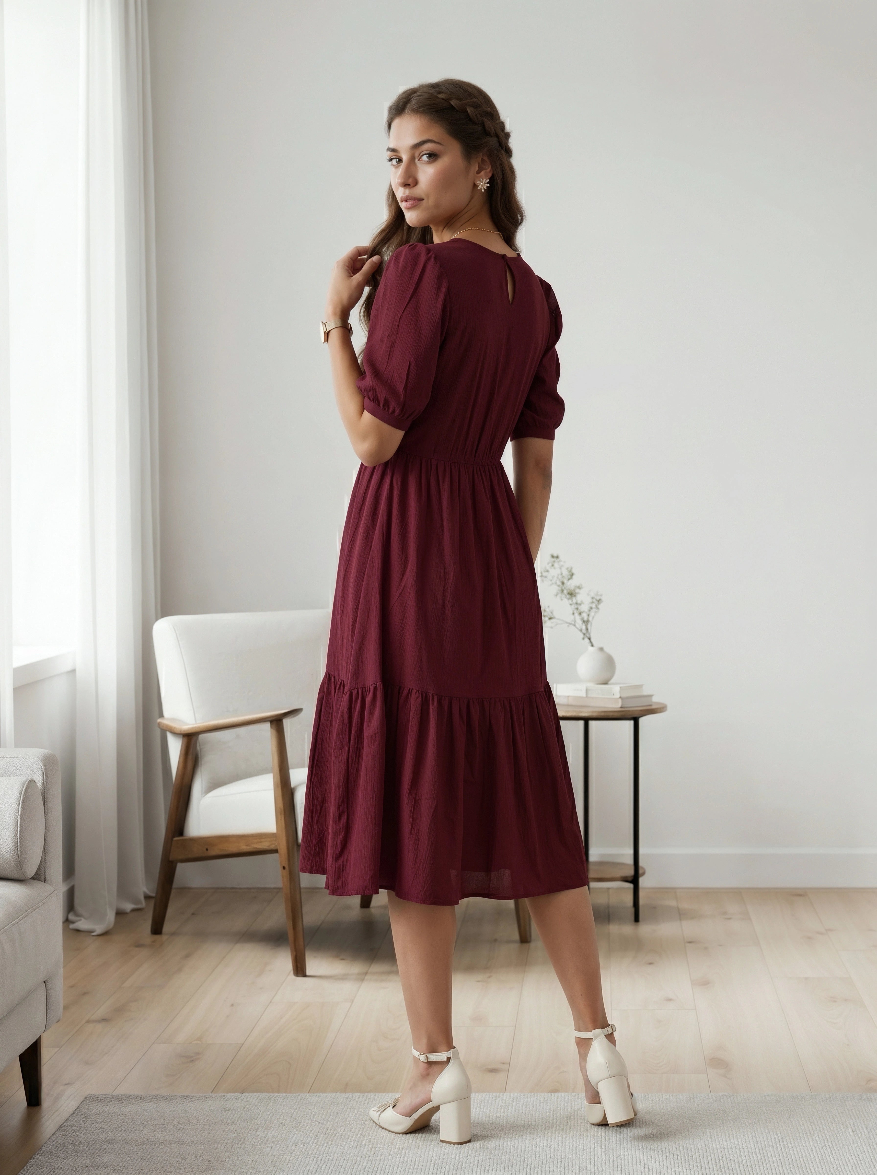 Woman in a burgundy dress standing in a room with neutral decor