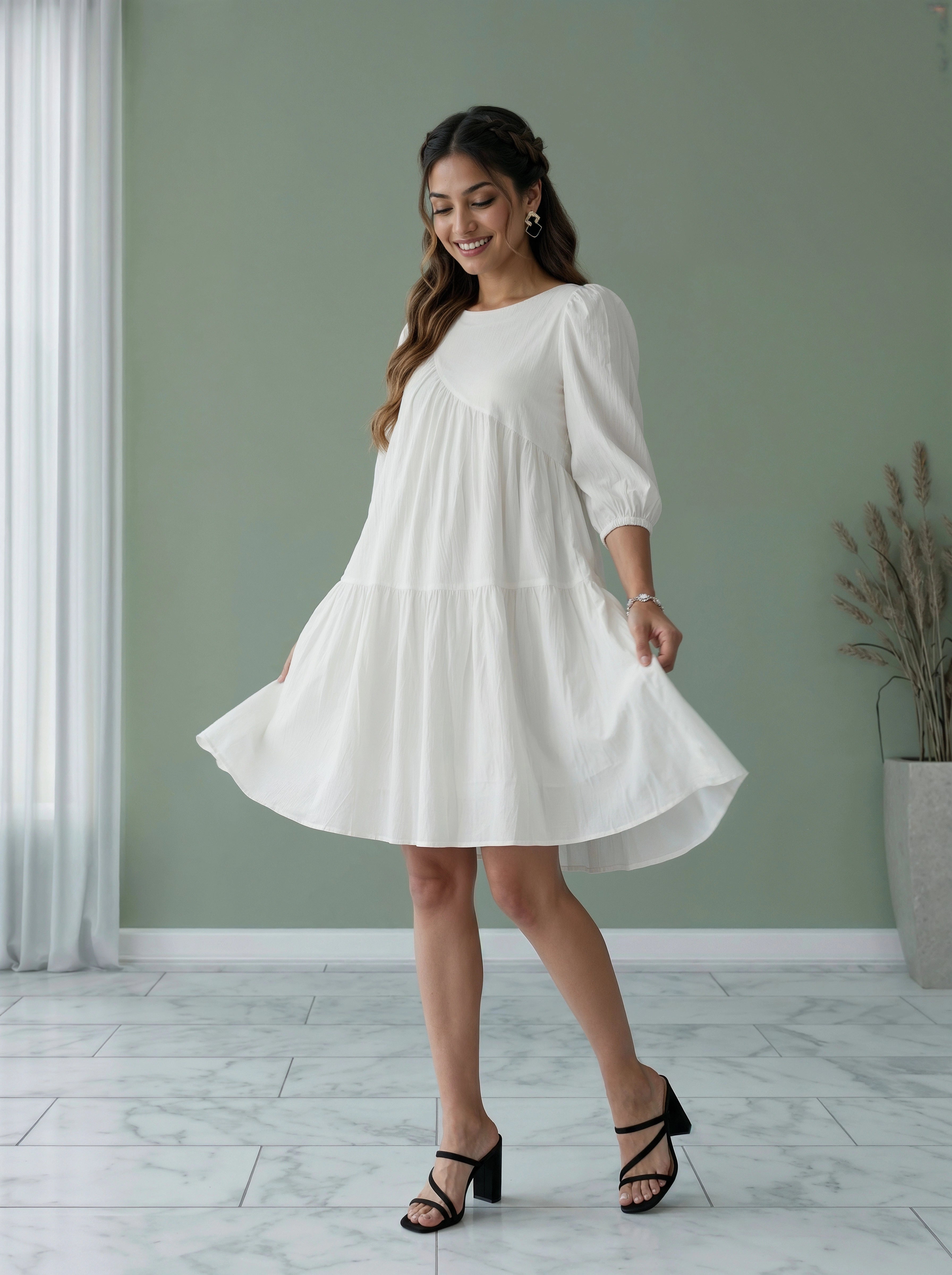 Woman in a white dress standing in a room with a green wall and white floor.