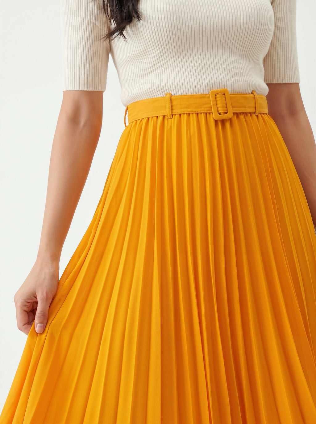 Person wearing a white top and bright yellow pleated skirt on a light background