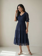Woman wearing a navy blue dress against a plain background