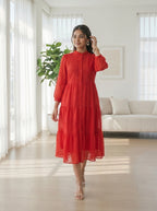 Woman in a red dress standing in a bright living room.