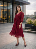 Woman in a red dress standing outdoors with modern building in the background