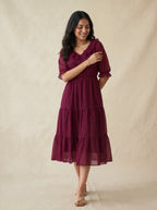 Woman wearing a burgundy dress against a beige background
