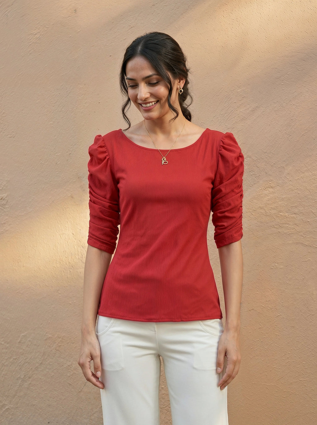 Woman wearing a red top with puff sleeves against a beige background