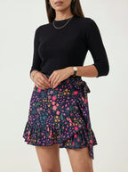 Woman wearing a black top and floral skirt on a white background