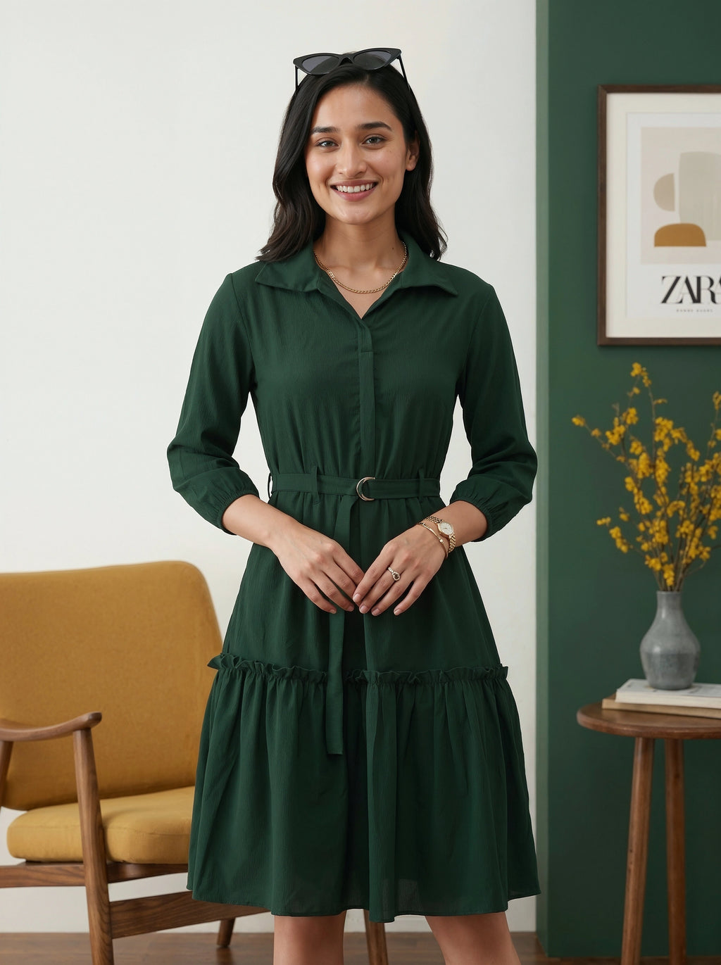 Woman wearing a green dress standing in a room with a yellow chair and decorative elements.
