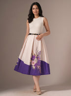 Woman wearing a white dress with purple floral design on a plain background