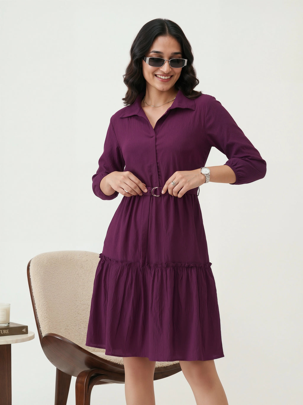 Woman wearing a purple dress with sunglasses on a white background
