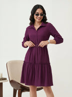 Woman wearing a purple dress with sunglasses on a white background