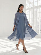 Woman wearing a blue dress with a matching cardigan in a bright room.