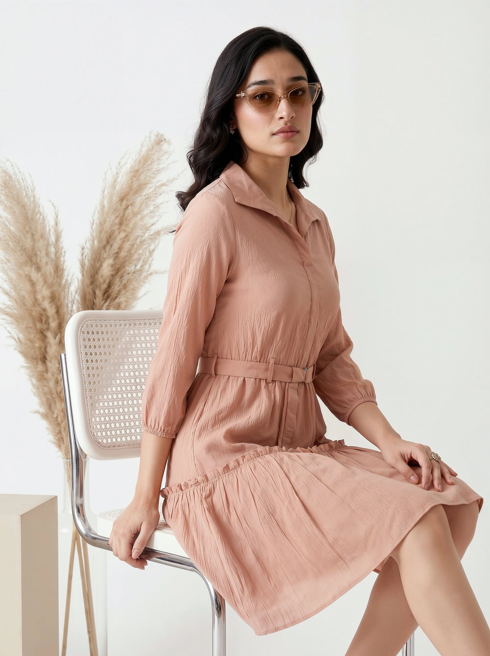 Woman in a pink dress sitting on a chair with decorative elements in the background