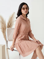 Woman in a pink dress sitting on a chair with decorative elements in the background