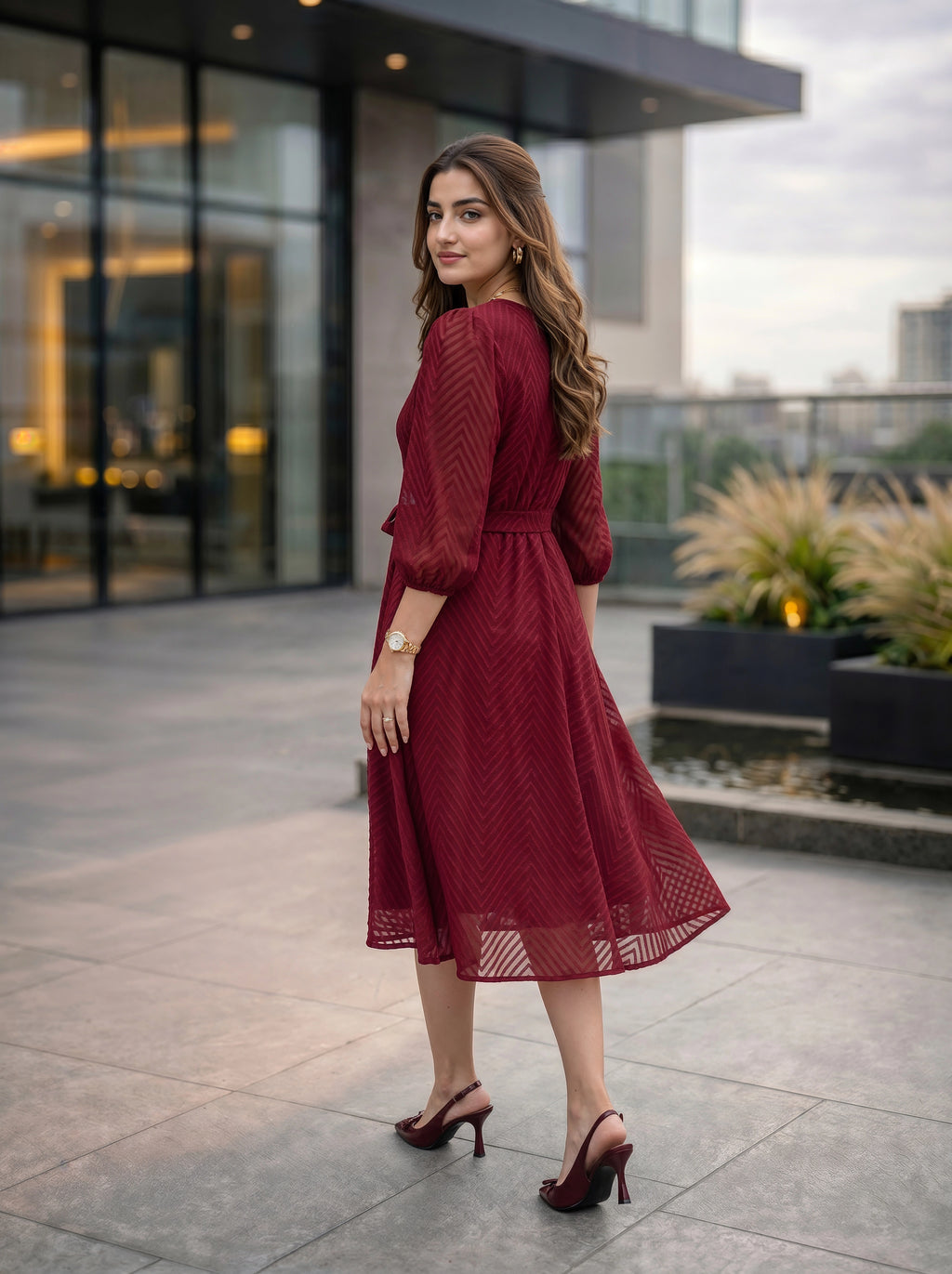 Woman in a red dress standing outdoors with modern building in the background