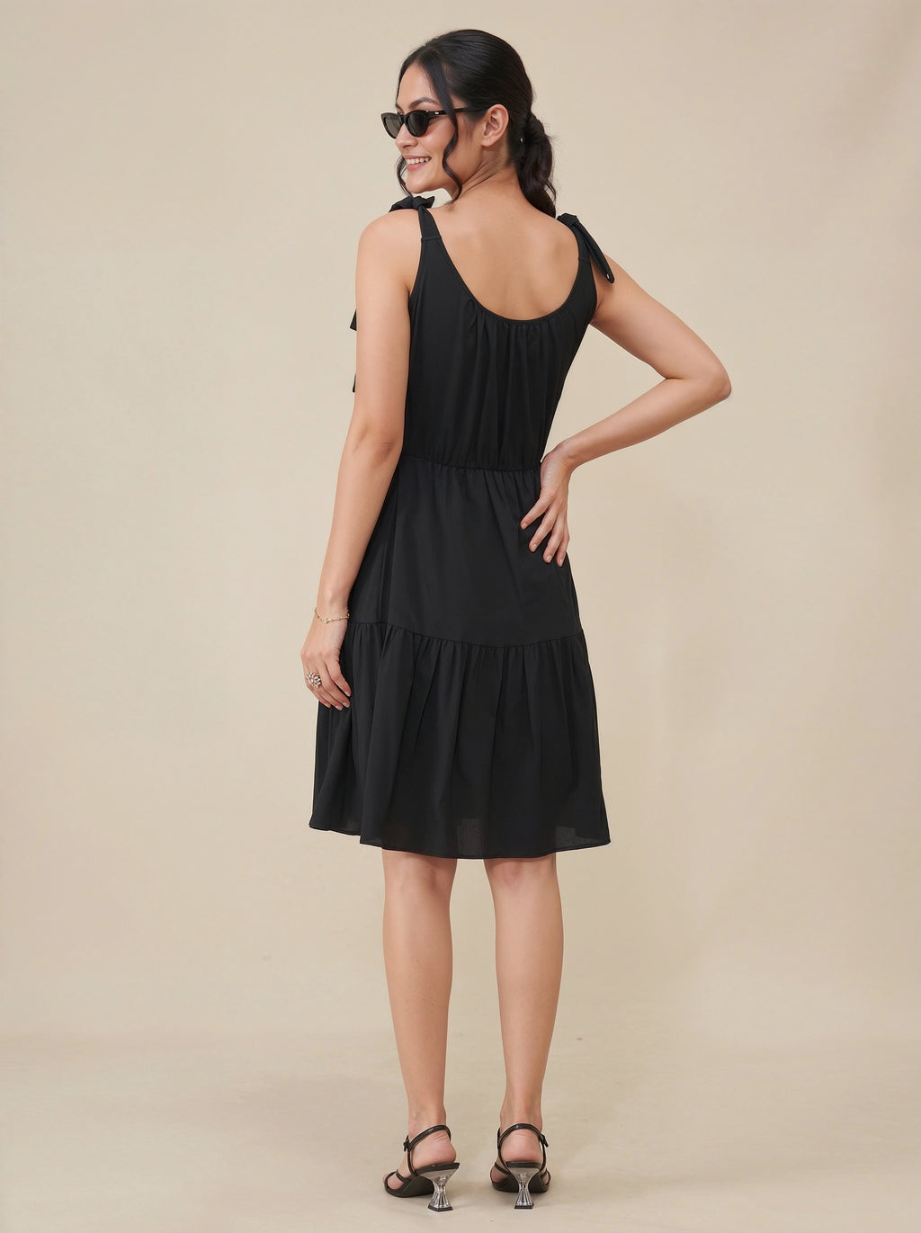 Woman wearing a black dress against a beige background
