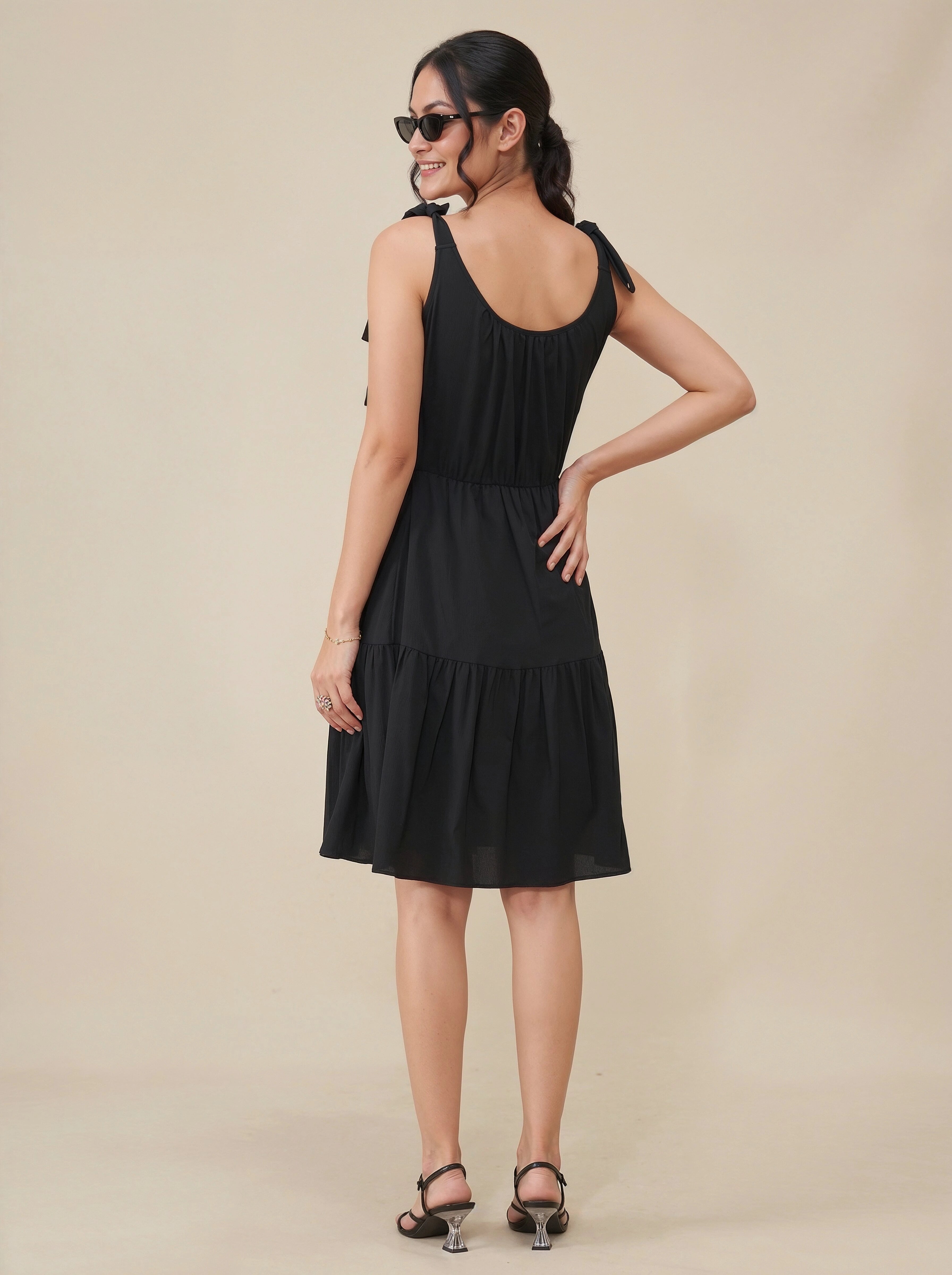Woman wearing a black dress against a beige background