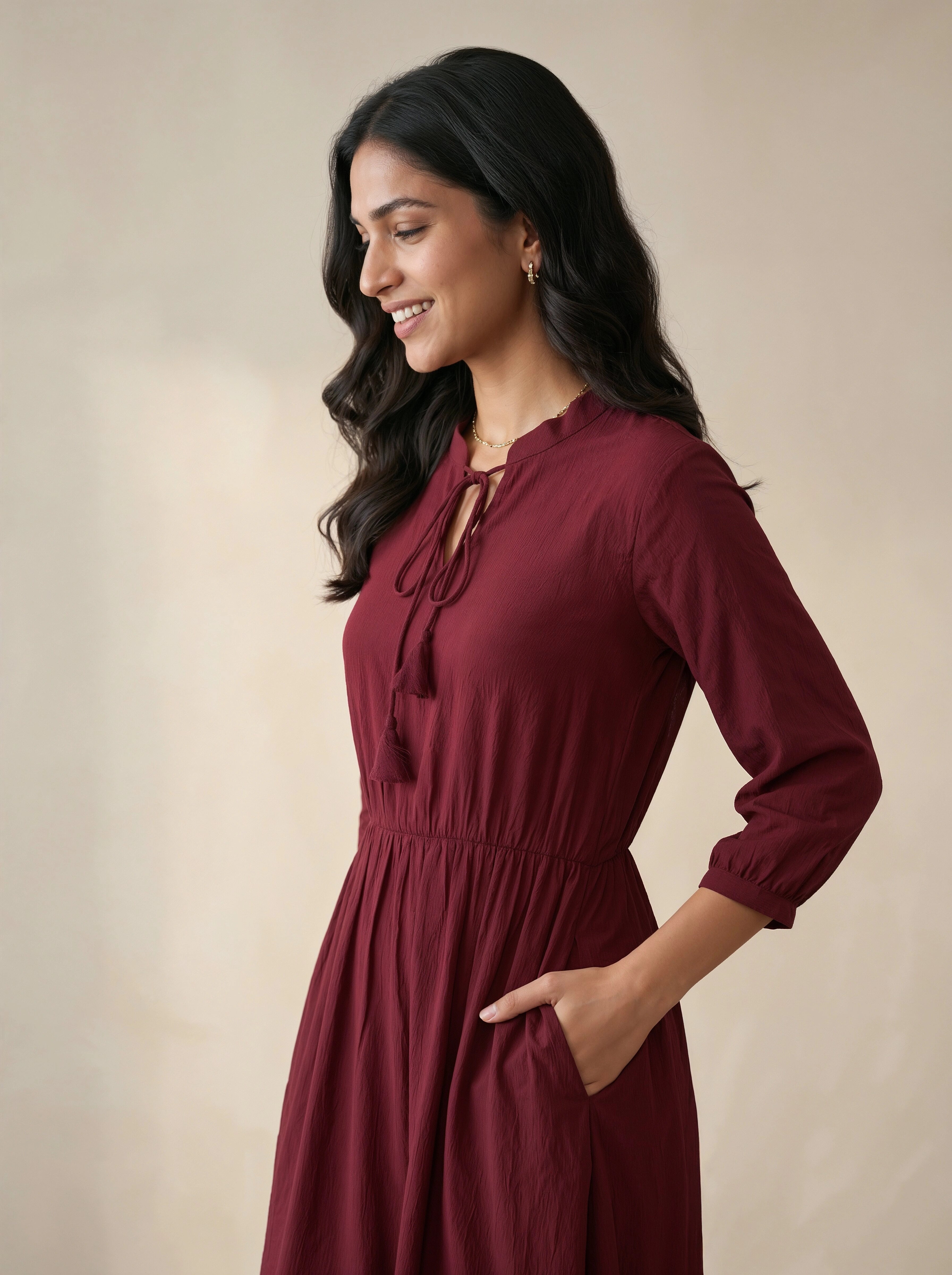 Woman wearing a burgundy dress against a beige background