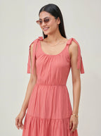 Woman wearing a pink dress with bow straps on a plain background
