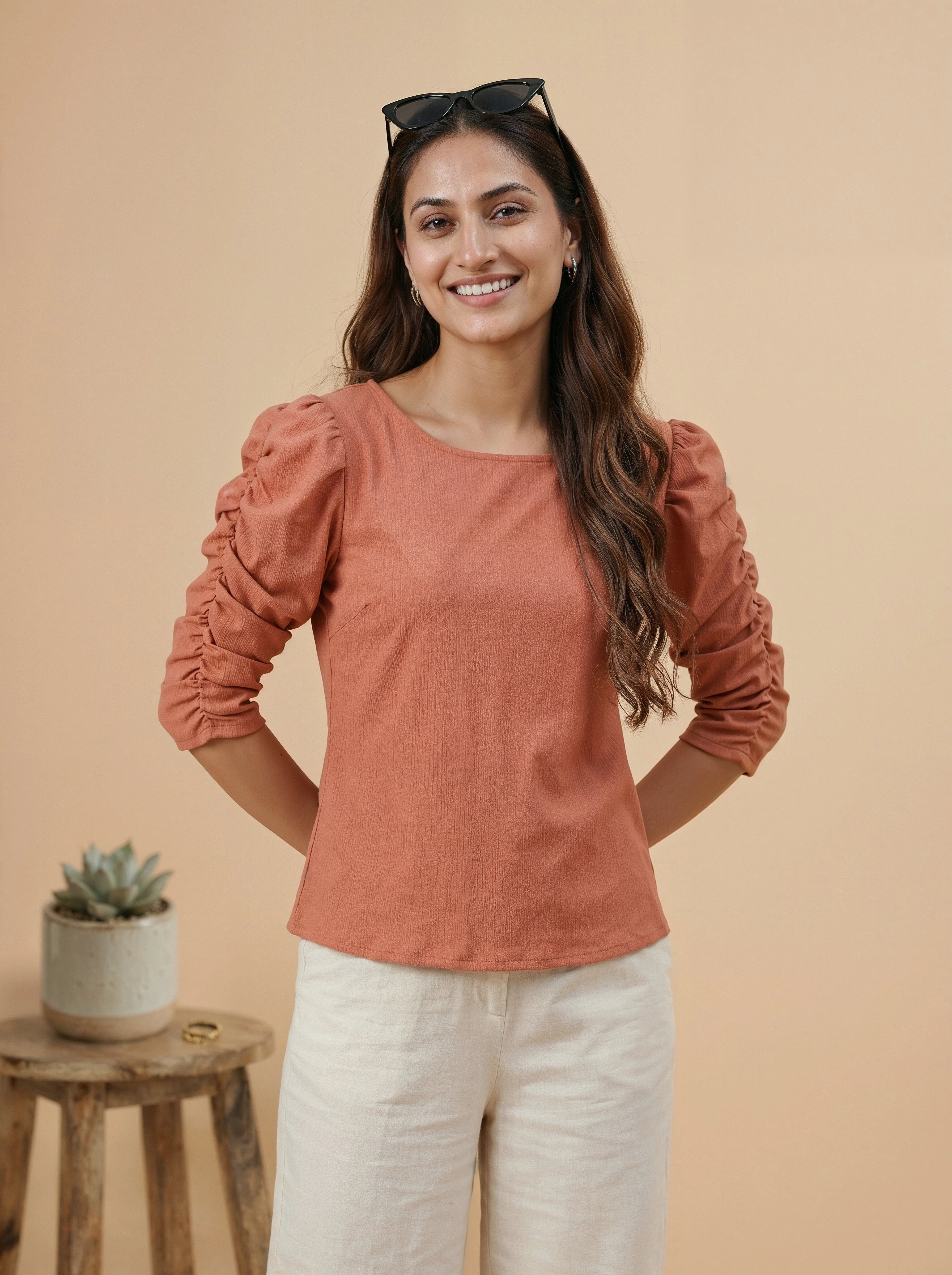 Woman wearing a rust-colored blouse with ruffled sleeves against a beige background