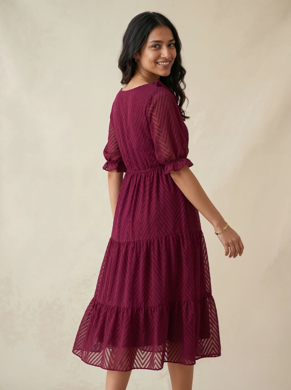 Woman wearing a burgundy dress against a beige background
