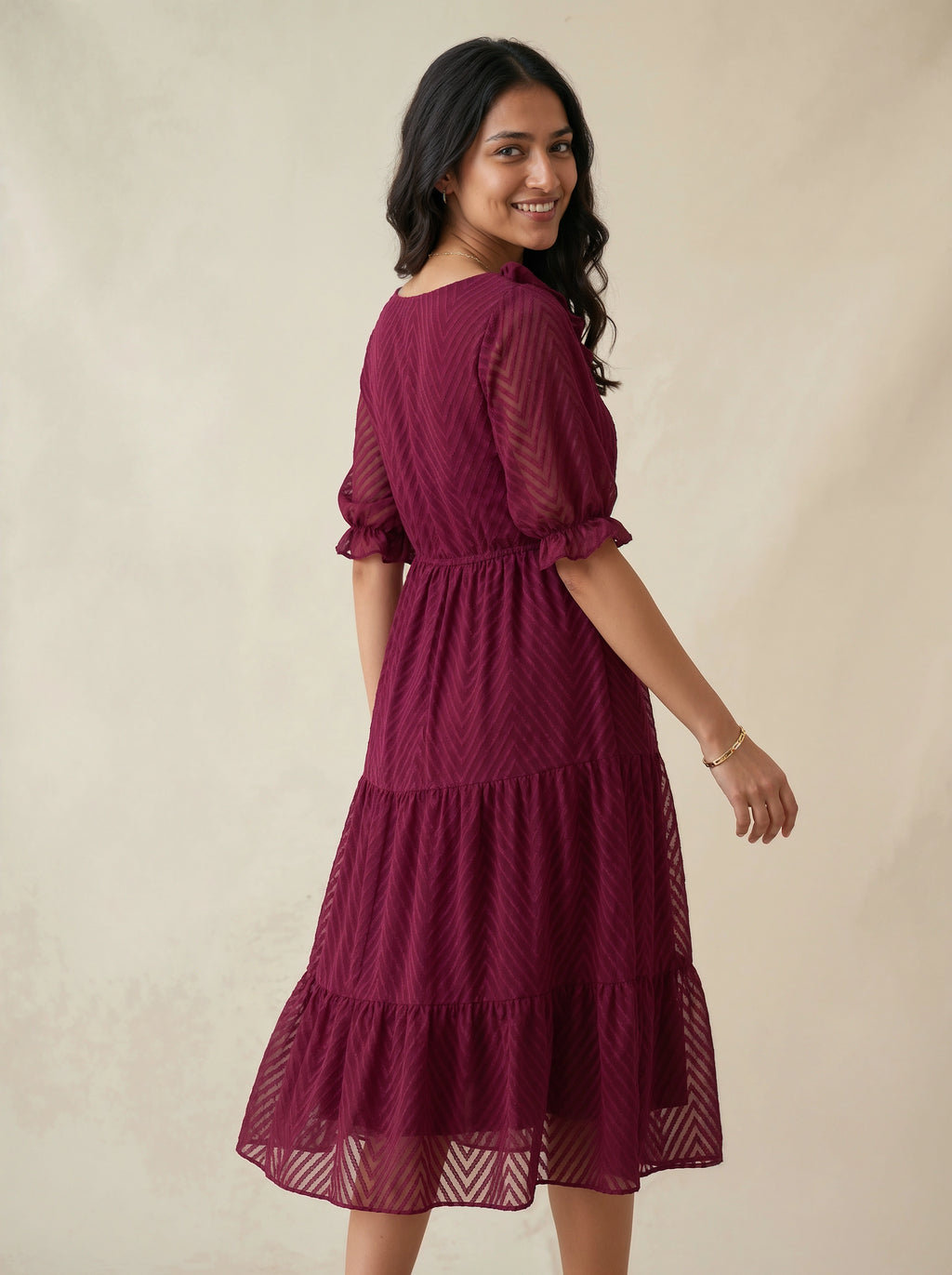 Woman wearing a burgundy dress against a beige background